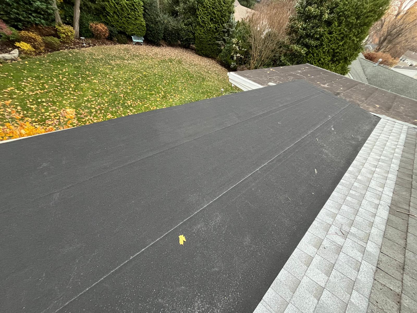 Completed flat rubber roof section adjacent to shingles